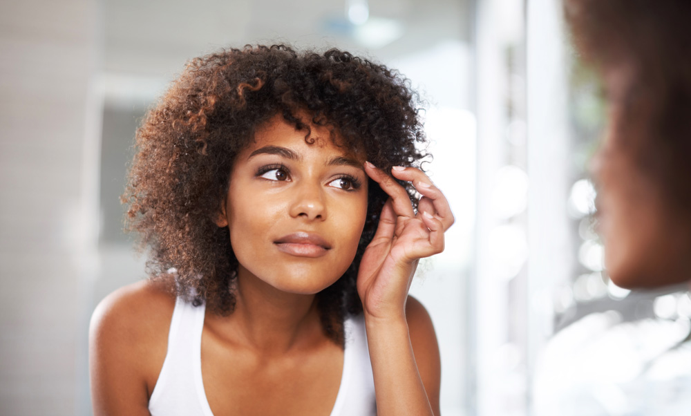Woman adjusting contact lens in a mirror